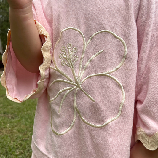Pink garment with a floral embroidery detail on a grassy background