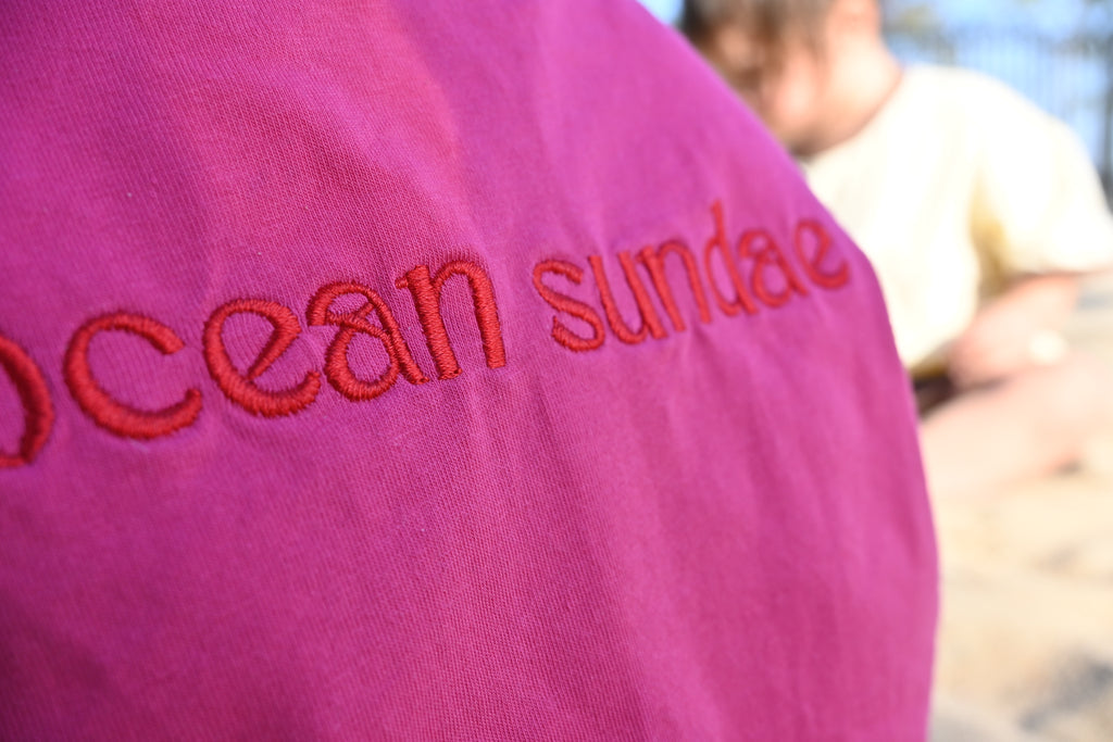 Close-up of a pink garment with 'Ocean Sundae' embroidered in red.