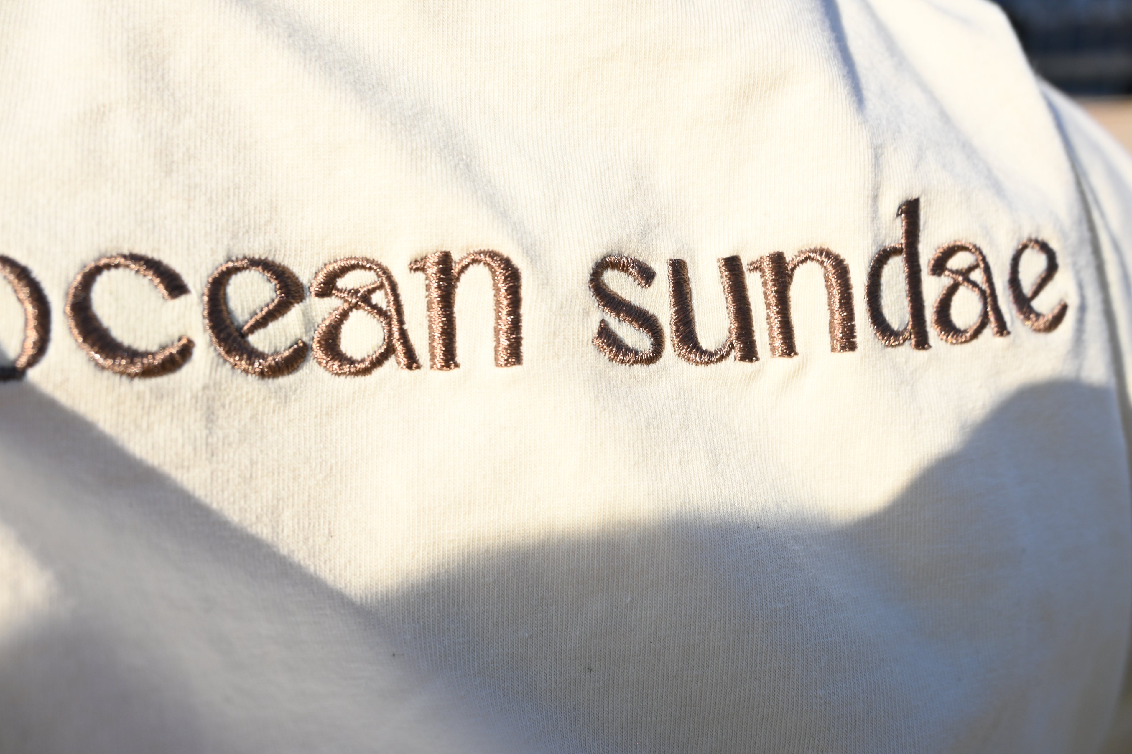 Text 'ocean sundae' embroidered on a white fabric background