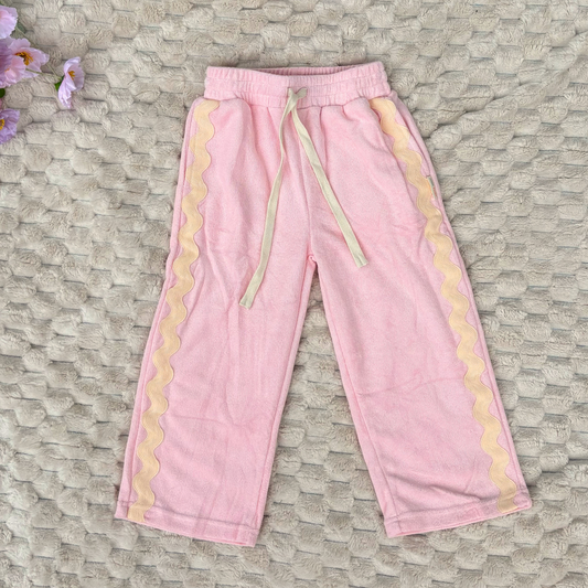 Pink sweatpants with cream trim on a textured surface