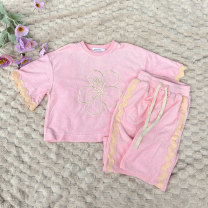 Pink children's outfit with floral design on a textured surface