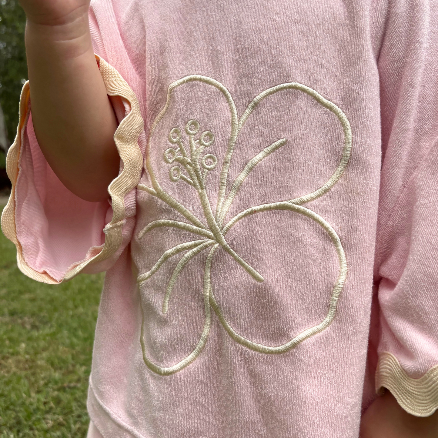 Pink garment with a floral embroidery detail on a grassy background