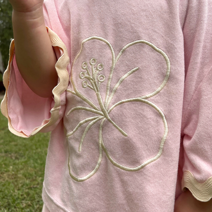 Pink garment with a floral embroidery detail on a grassy background