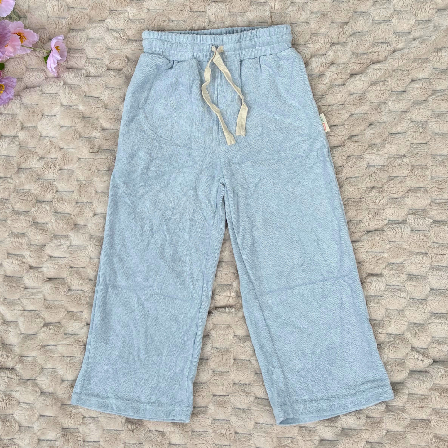 Light blue pants with a drawstring on a textured stone surface.