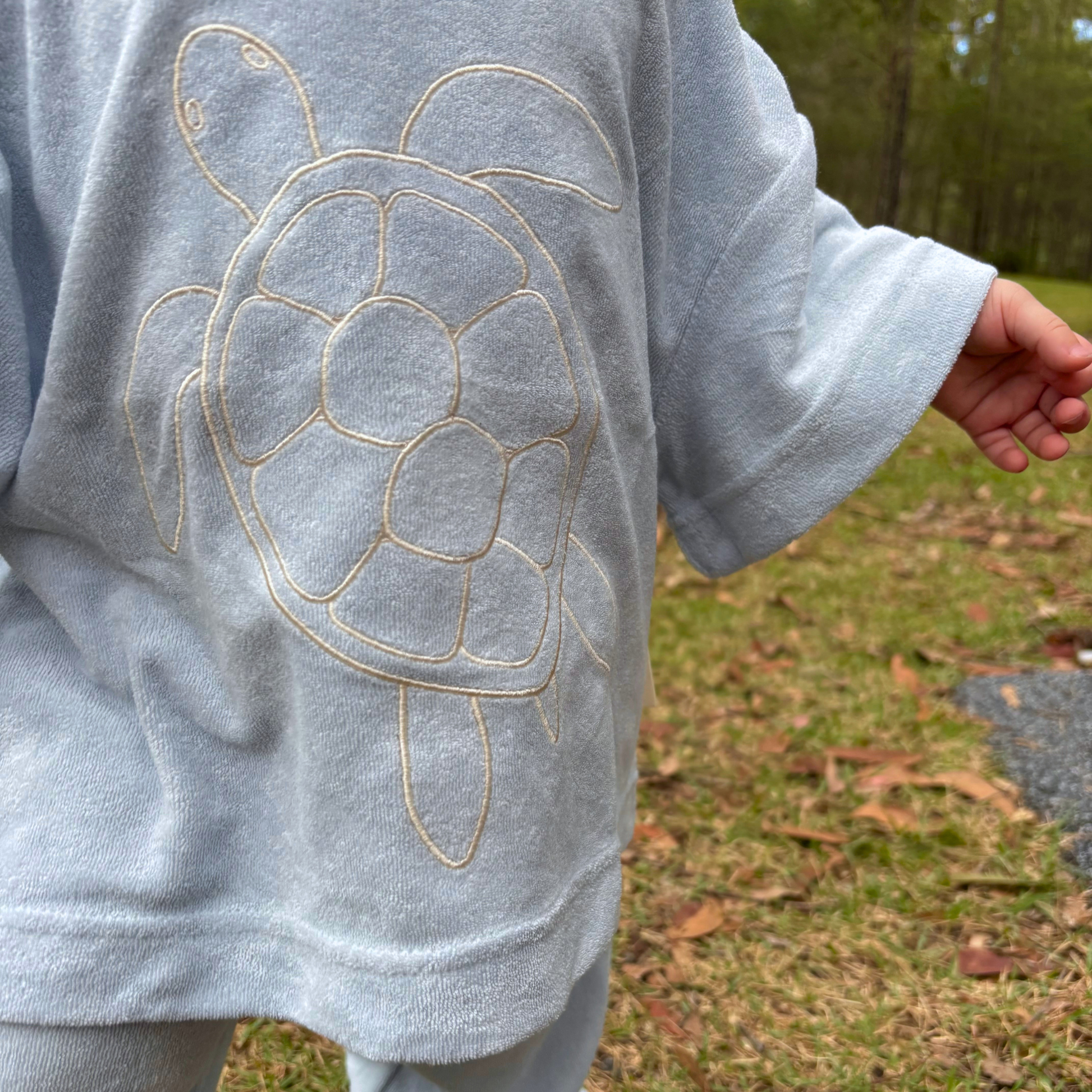 Light blue sweatshirt with turtle design worn outdoors