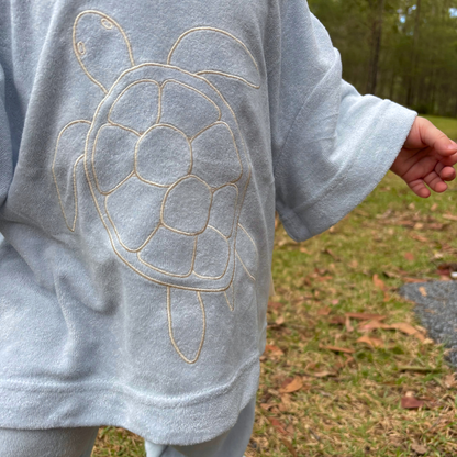 Light blue sweatshirt with turtle design worn outdoors