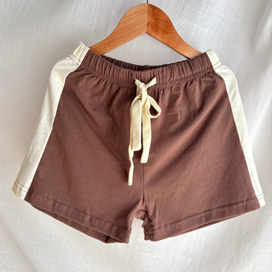 Brown shorts with beige stripes on a hanger against a light background